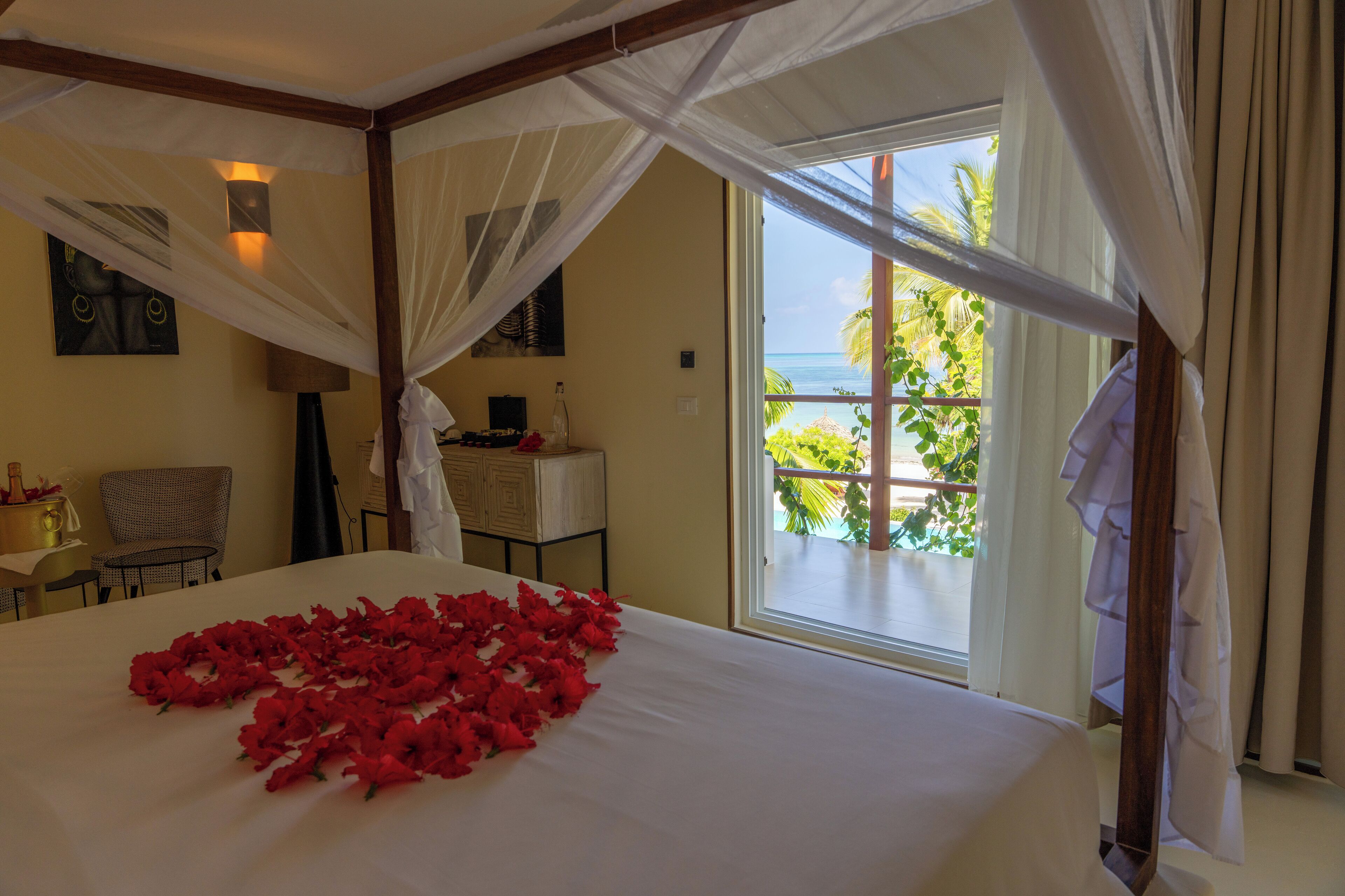 A room with a bed, a chair, a table, and a window with a view of the ocean.