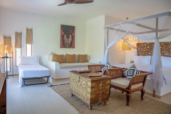 A bedroom with a bed, a sofa, a wooden chest, and a canopy bed.