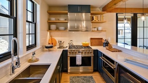 A modern kitchen with a stainless steel stove, black cabinets, and a large window.
