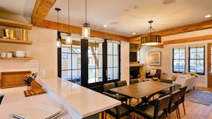 Una cocina amplia con una isla grande, vigas de madera e iluminación colgante.