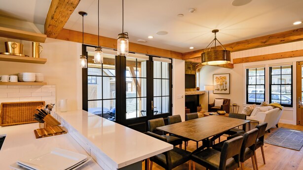 A spacious kitchen with a large island, wooden beams, and pendant lighting.