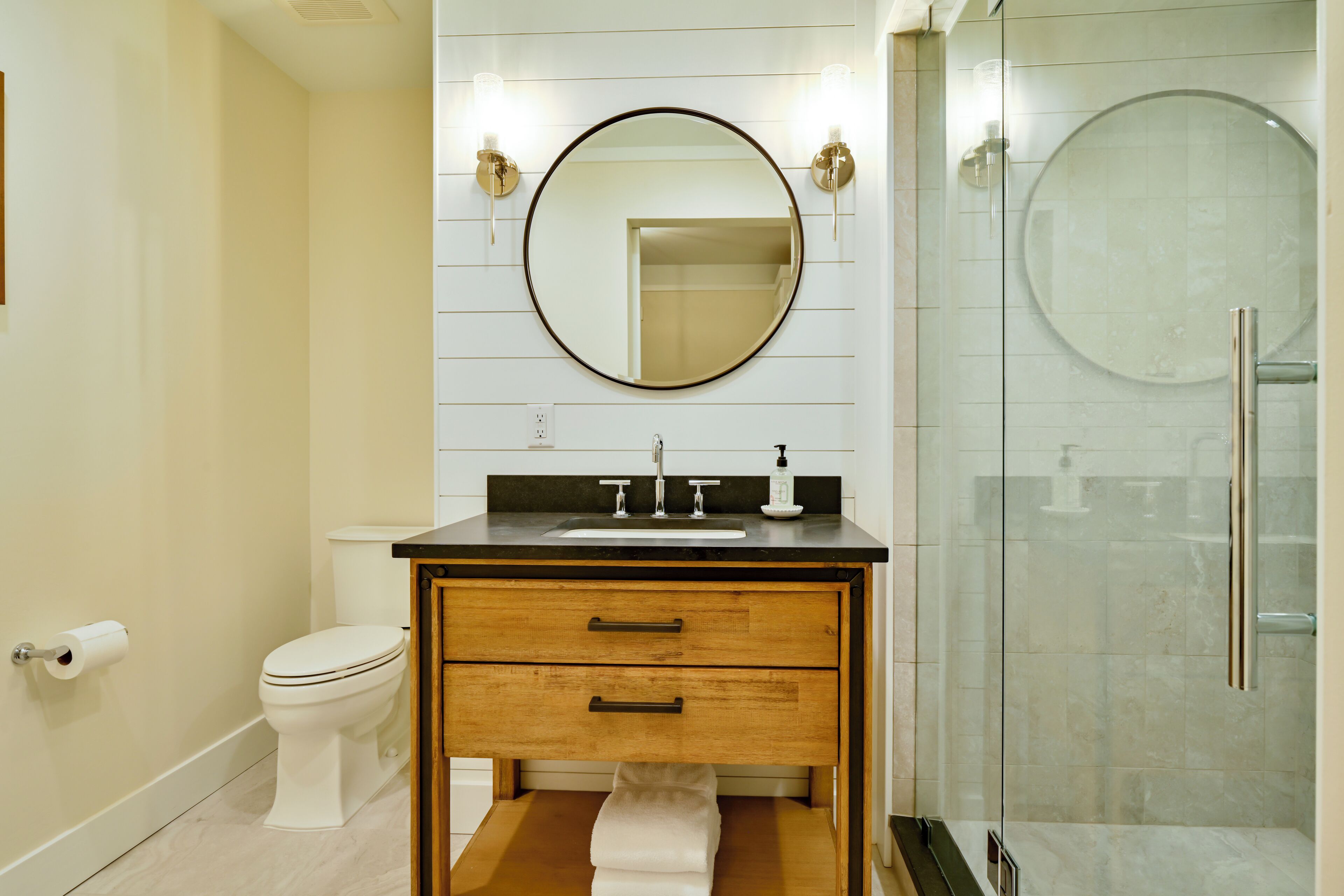 A modern bathroom with a toilet, sink, vanity, and a glass shower enclosure.