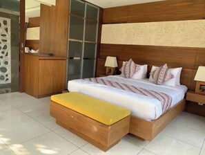 Relax in a spacious room with a large bed, two bedside lamps, and a comfortable bench.
