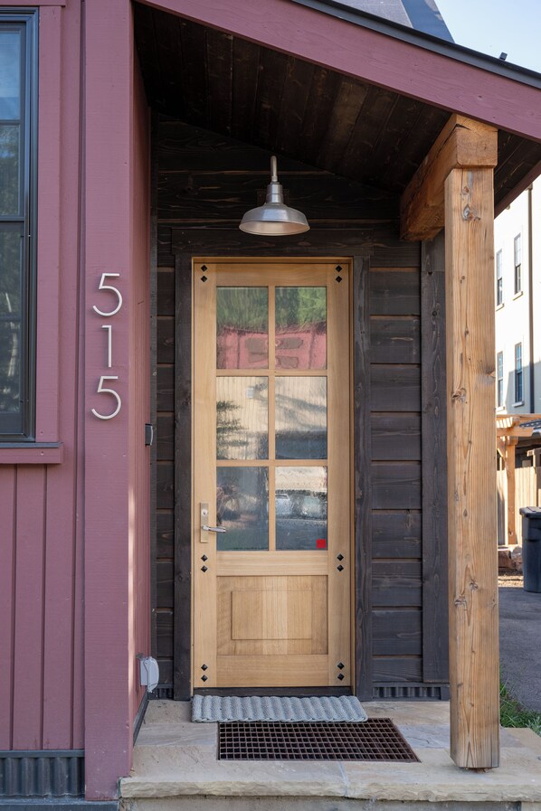 A wooden door with a glass panel, a metal doorbell, and a number '515' on the wall.