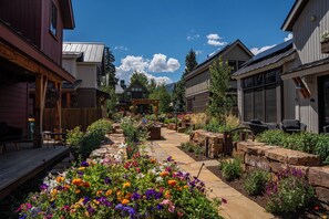 Un quartier résidentiel doté d’un chemin pavé, d’un espace extérieur aménagé pour s’asseoir et d’une variété de plantes à fleurs.