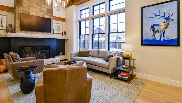 A cozy living room with a fireplace, comfortable seating, and large windows. - Academy Place | Bluebell (Crested Butte)