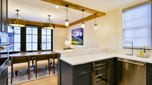A modern kitchen with a wooden ceiling, stainless steel appliances, and a large island. - Academy Place | Bluebell (Crested Butte)