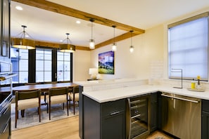 A modern kitchen with a wooden ceiling, stainless steel appliances, and a large island. - Academy Place | Bluebell (Crested Butte)