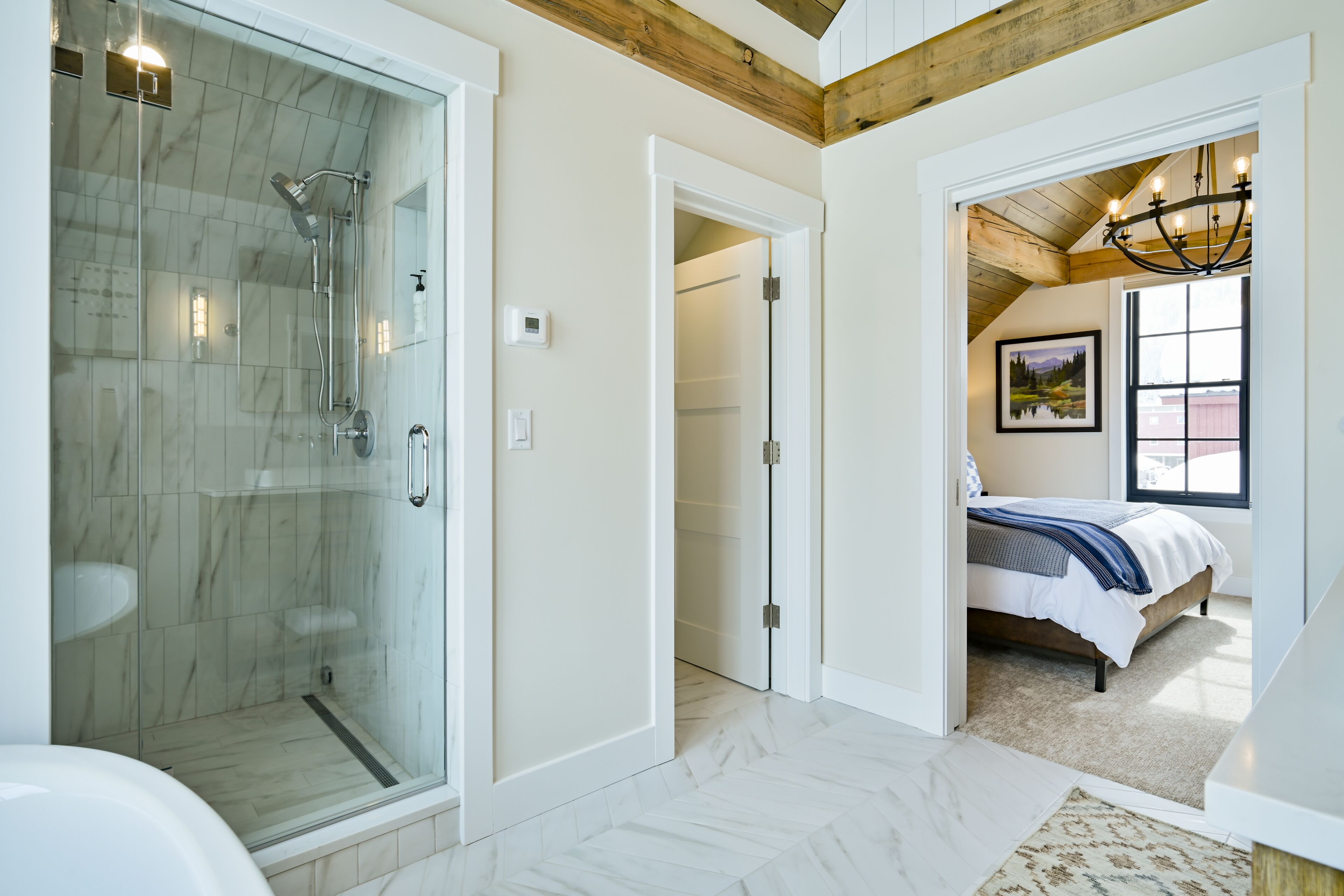 A modern bathroom with a glass-enclosed shower, a white bathtub, and a marble floor.