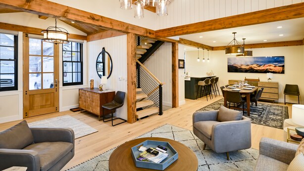 A spacious living area with a wooden staircase, a dining area, and a large painting on the wall. - Fairy Slipper at Academy Place (Crested Butte)