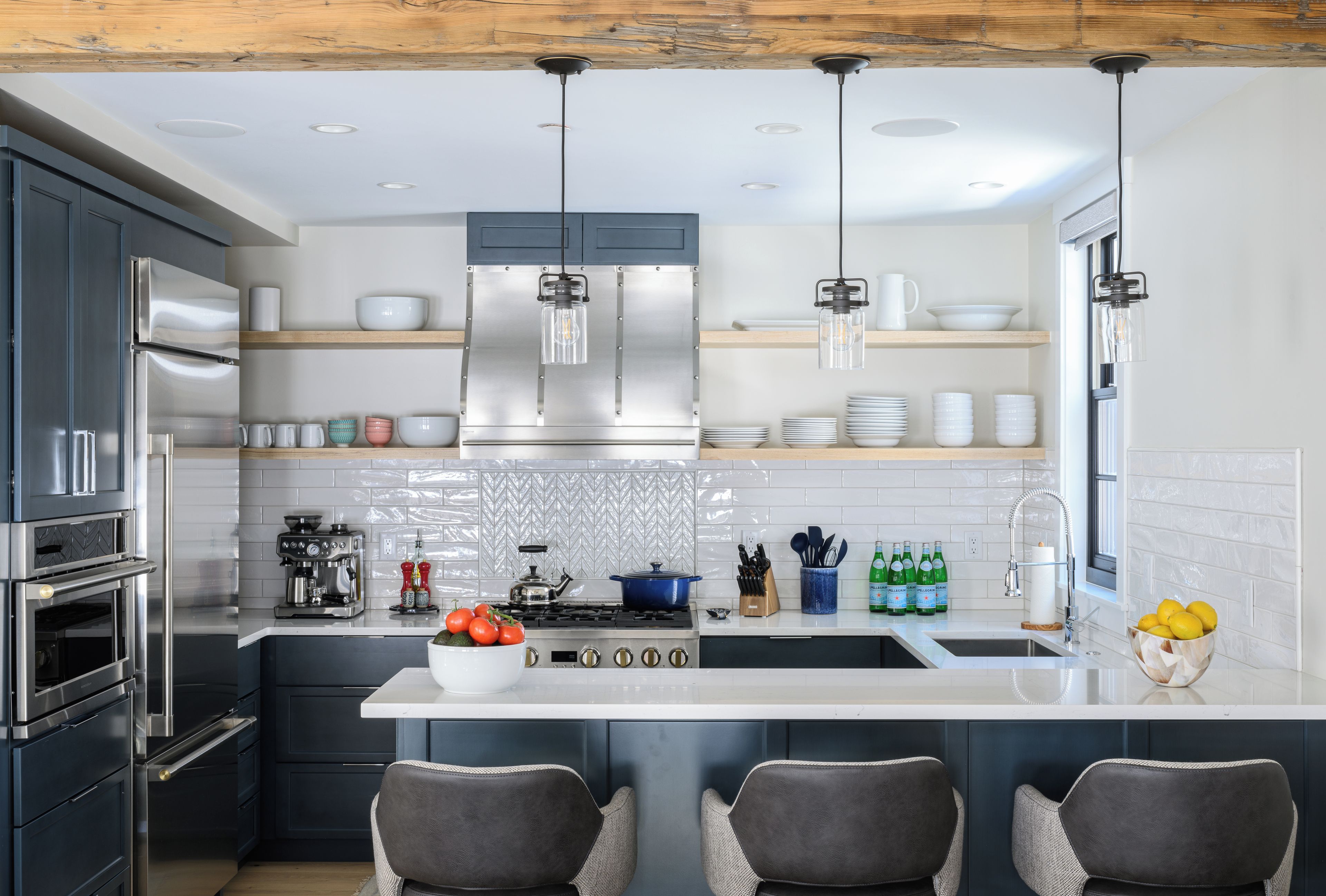 A modern kitchen with stainless steel appliances, a central island, and bar seating.