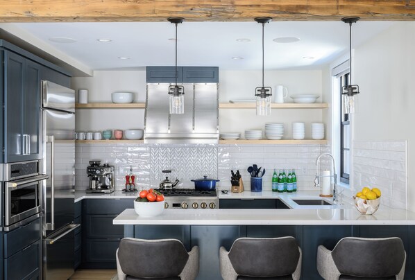 A modern kitchen with stainless steel appliances, a central island, and bar seating.