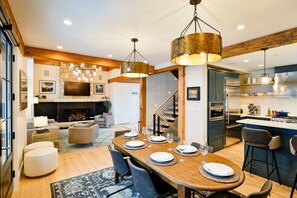 A modern kitchen with stainless steel appliances, wooden beams, and a dining area with a wooden table set for six.