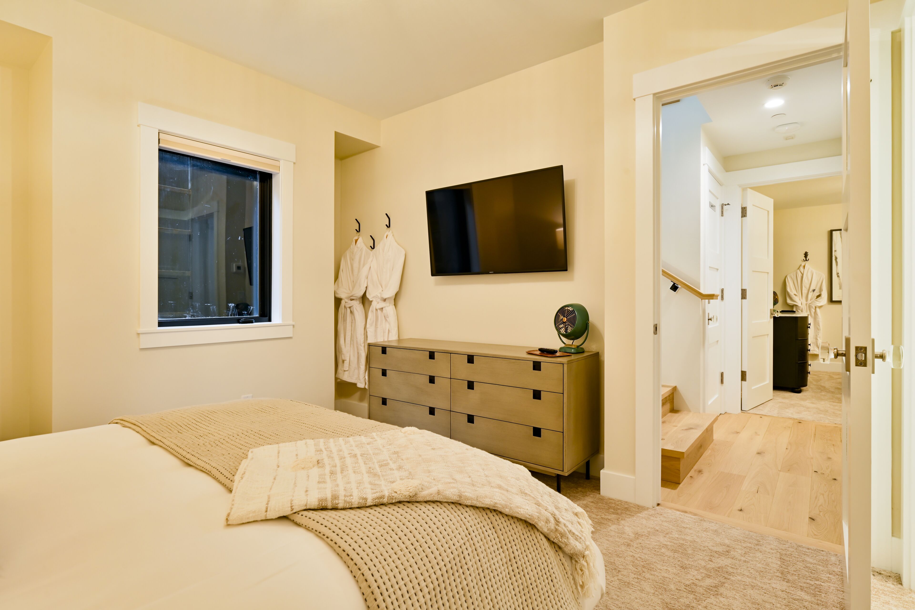 Une chambre à coucher avec un lit, une commode, un téléviseur et une fenêtre.