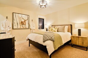 A bedroom with a bed, bedside tables, a wardrobe, a window, and a wall-mounted artwork of a deer.