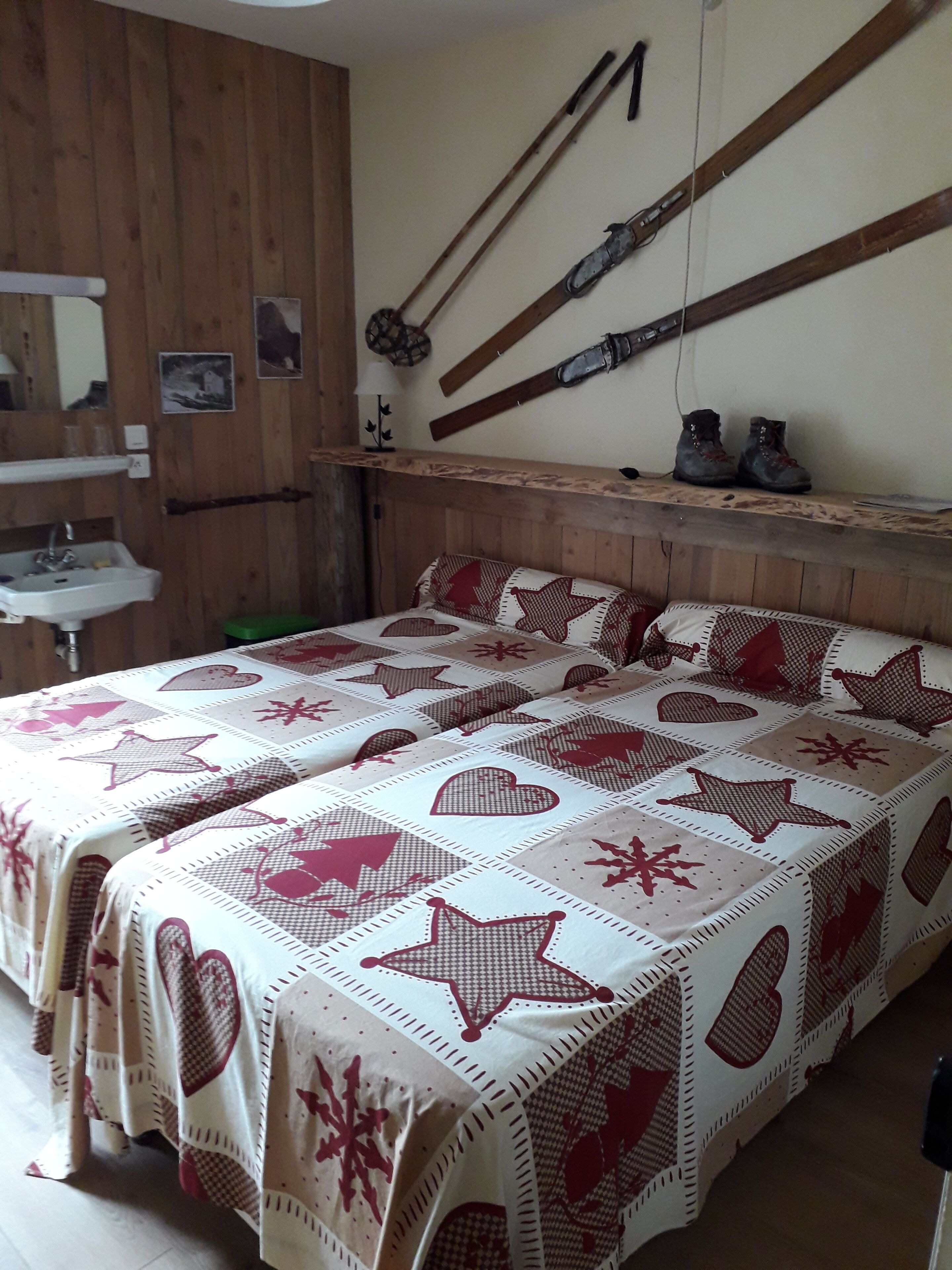Una camera da letto con una testiera in legno, una coperta con motivi a cuori e stelle, e uno scaffale con stivali e un cesto.