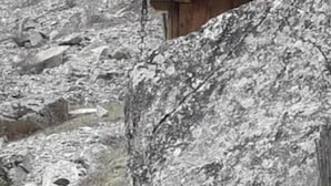 A rustic cabin with a wooden exterior, surrounded by large rocks and a grassy area.