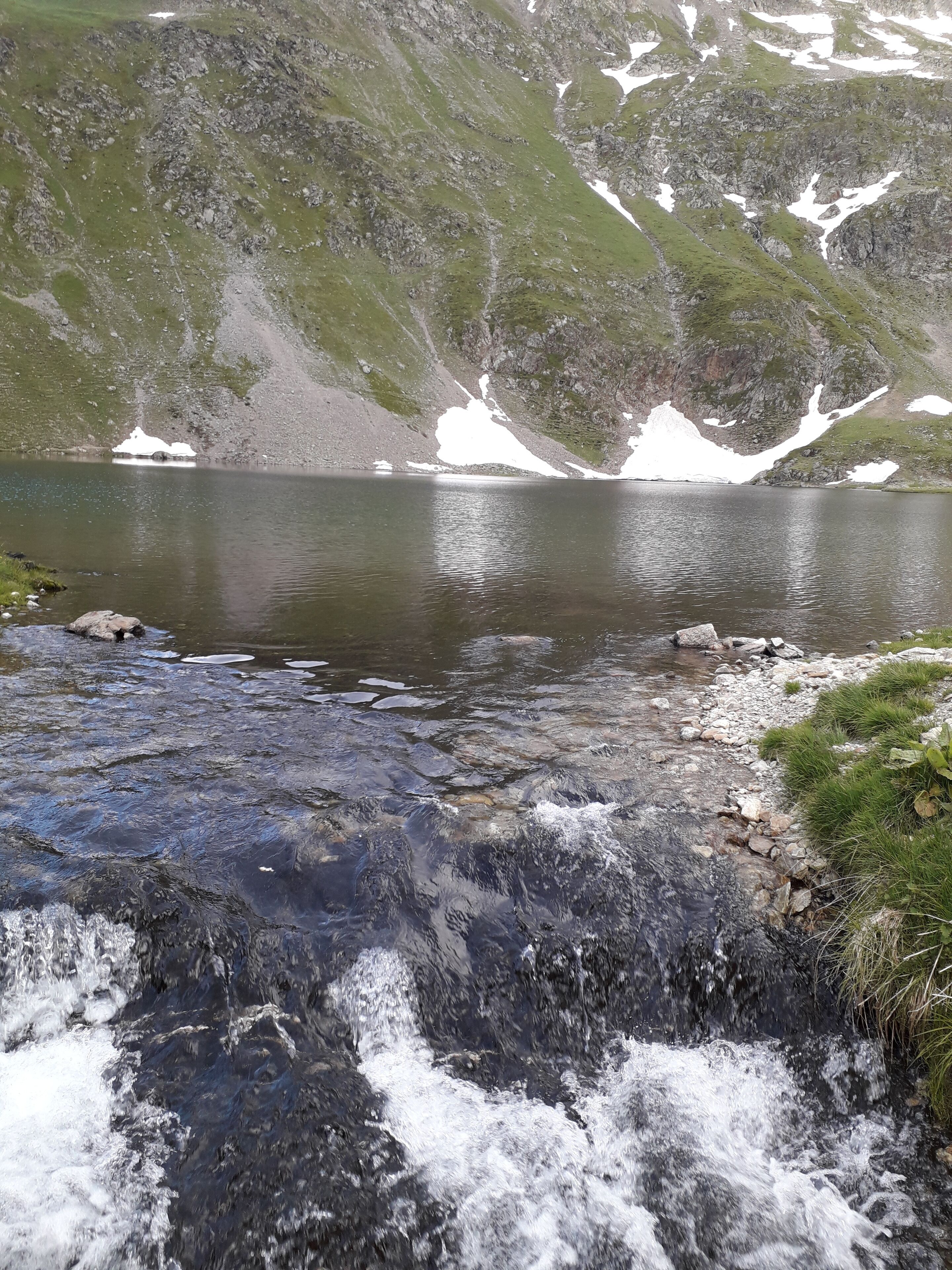 A mountain lake with a flowing stream in the foreground.