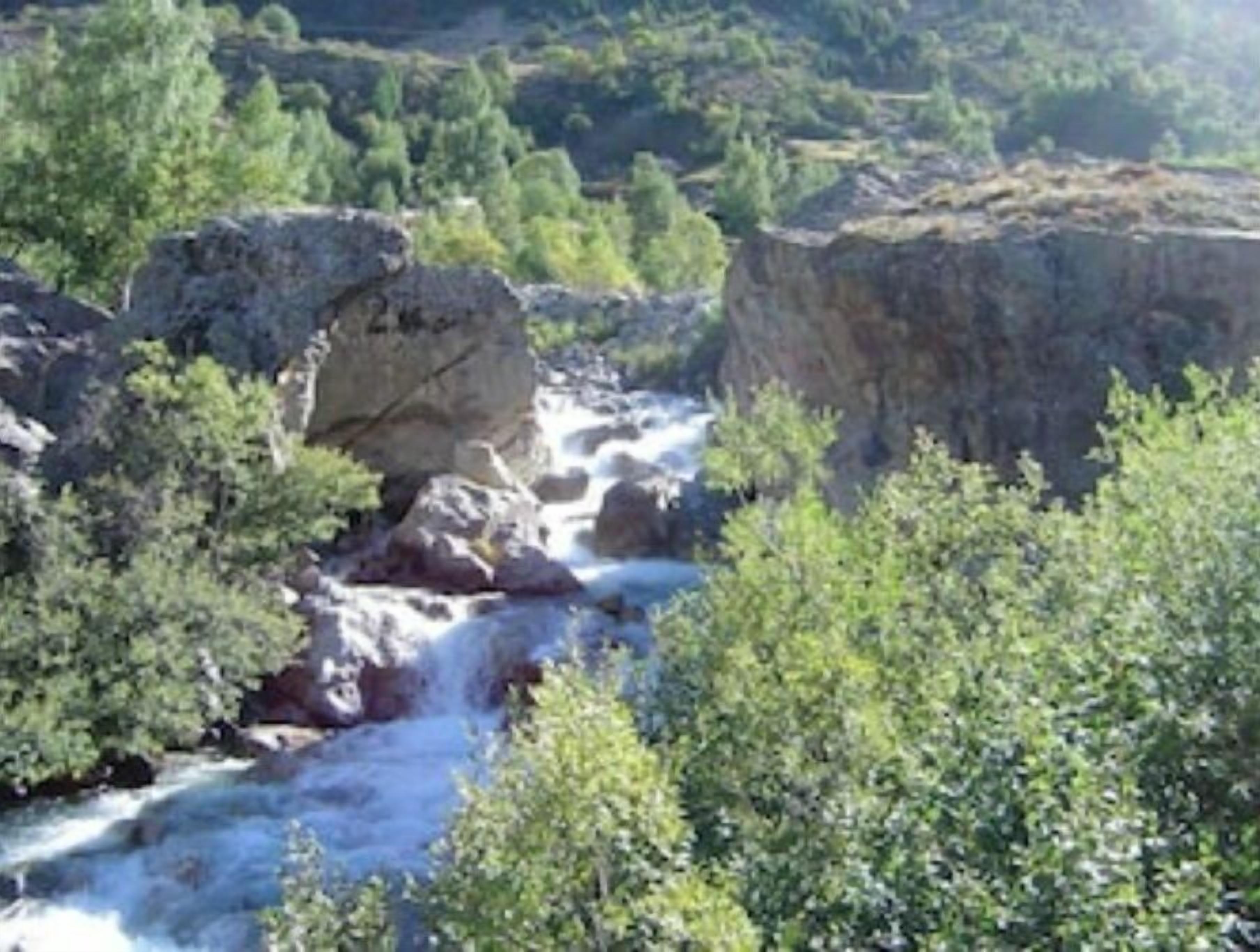 Une rivière qui traverse un paysage rocheux, bordé d’une végétation luxuriante.