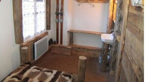 A rustic wooden room with a window, a wooden bench, and a mounted ski rack.