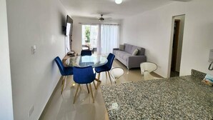 A modern living space with a dining area, a sofa, and a television.
