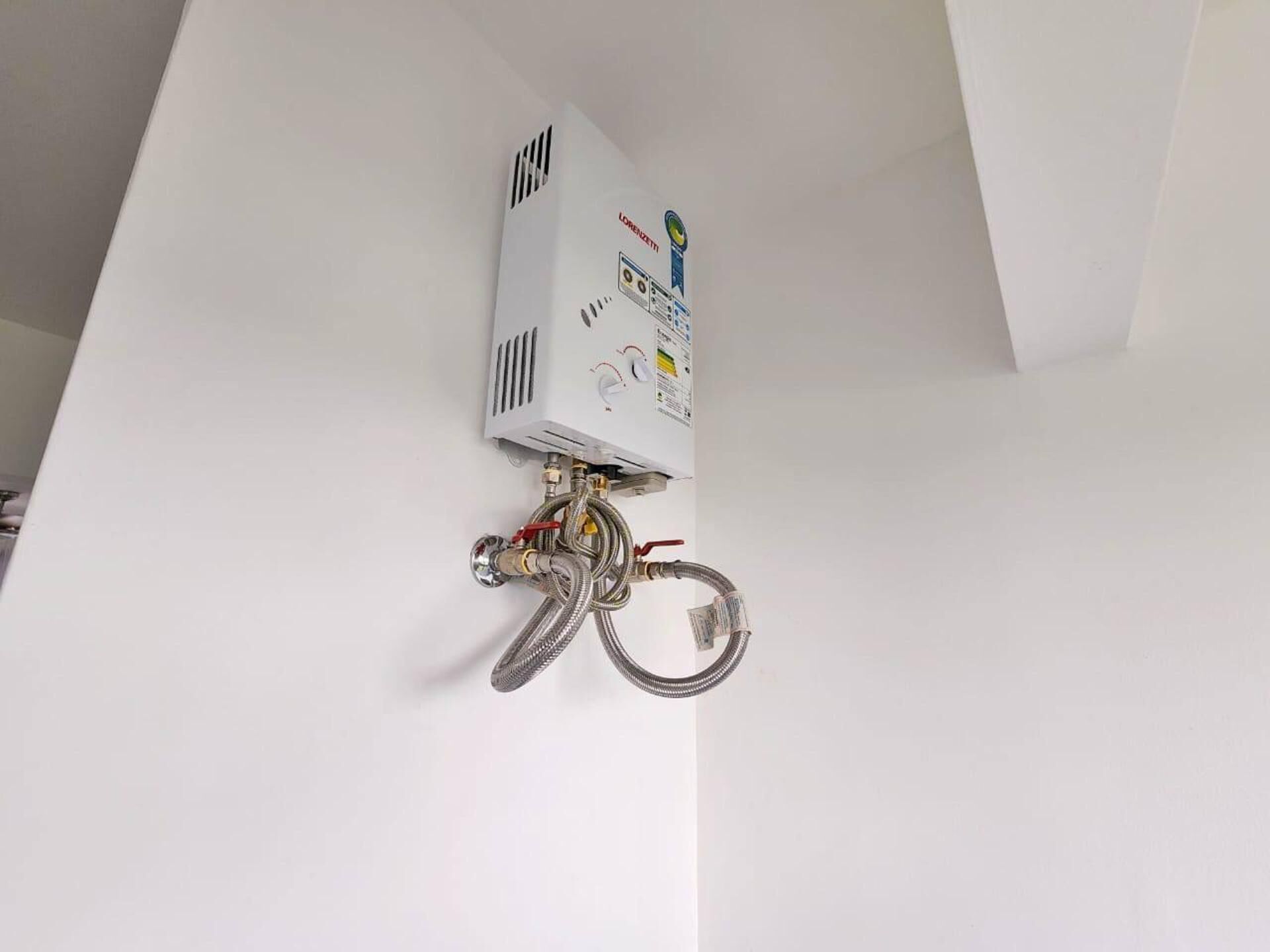 A white wall-mounted heater with visible control knobs and safety labels.