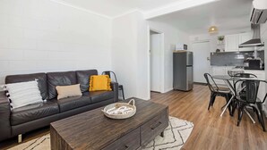 Ein modernes Wohnzimmer mit einer dunkelbraunen Ledersofa, einem Holztisch und einem Essbereich mit schwarzen Stühlen.