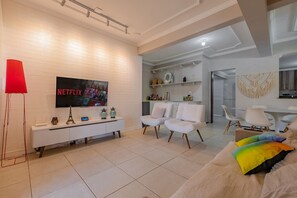 A modern living room with a white TV, white sofas, and a white console table.