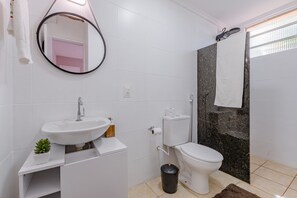 Un baño moderno con lavamanos, inodoro y ducha blancos.