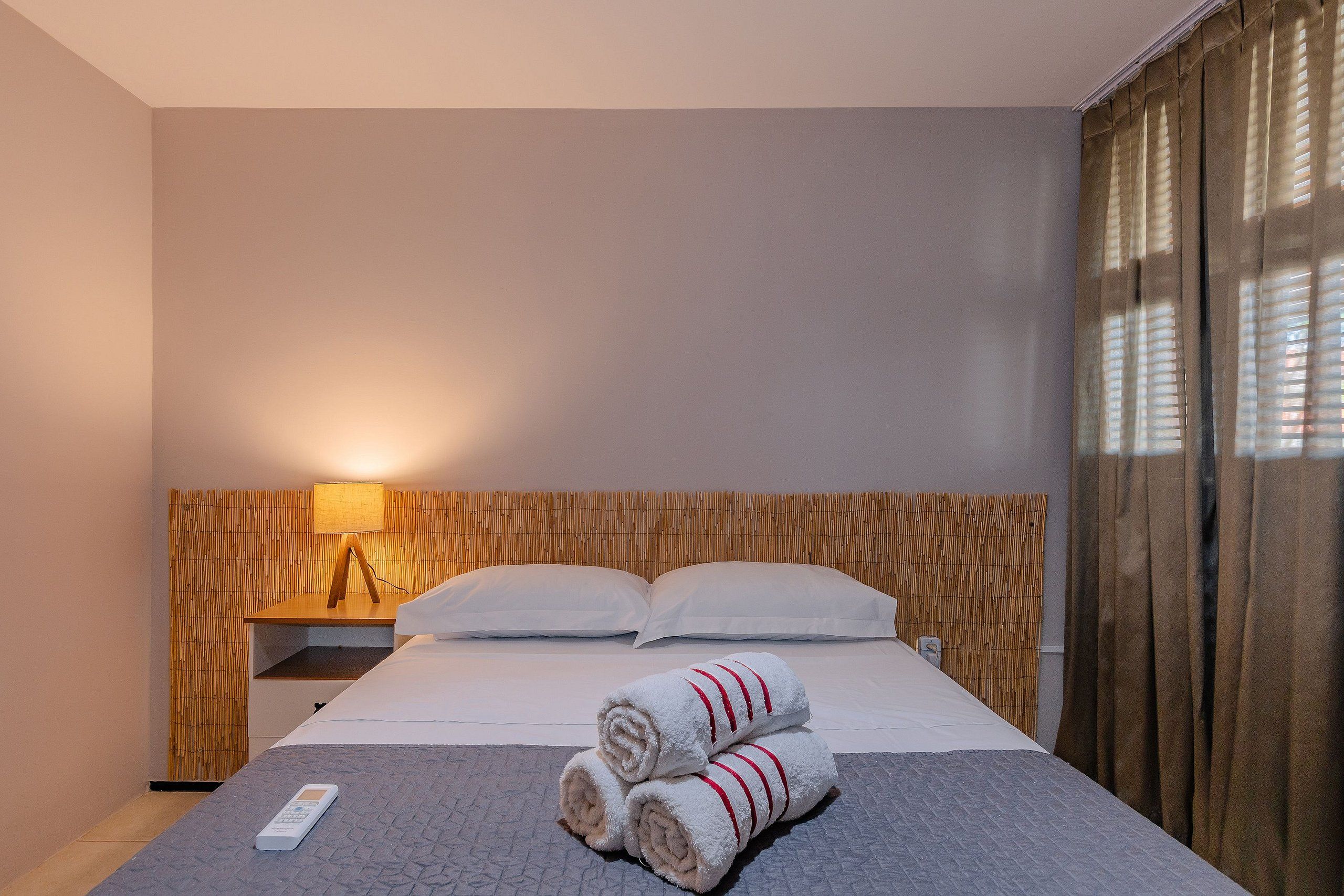 Una habitación de hotel con una cama, una mesita de noche, una lámpara y un control remoto.