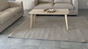 Una sala de estar moderna con un sofá beige, un sillón a juego y una mesa de centro de madera con una bandeja.