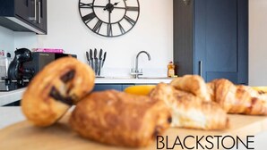 A kitchen with a clock, a toaster, and a cutting board with pastries. - Avery House - 1 Bed with Outdoor Terrace (Darlington)