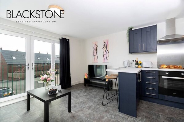 A modern kitchen with dark cabinets, a large island, and a dining area with a table and chairs.