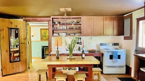 A kitchen with wooden cabinets, a central island with stools, a stove, and various kitchen items.