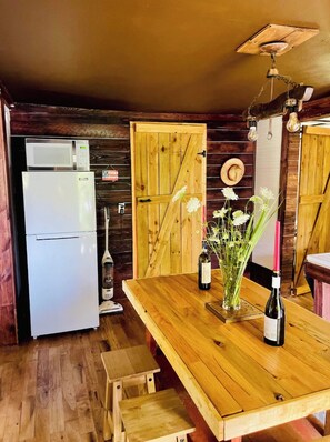 Eine rustikale Küche mit Holzwänden, einem weißen Kühlschrank, einem Holztisch mit Blumenvase und einer Holztür.
