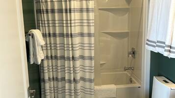 A bathroom with a shower, toilet, and marble flooring.