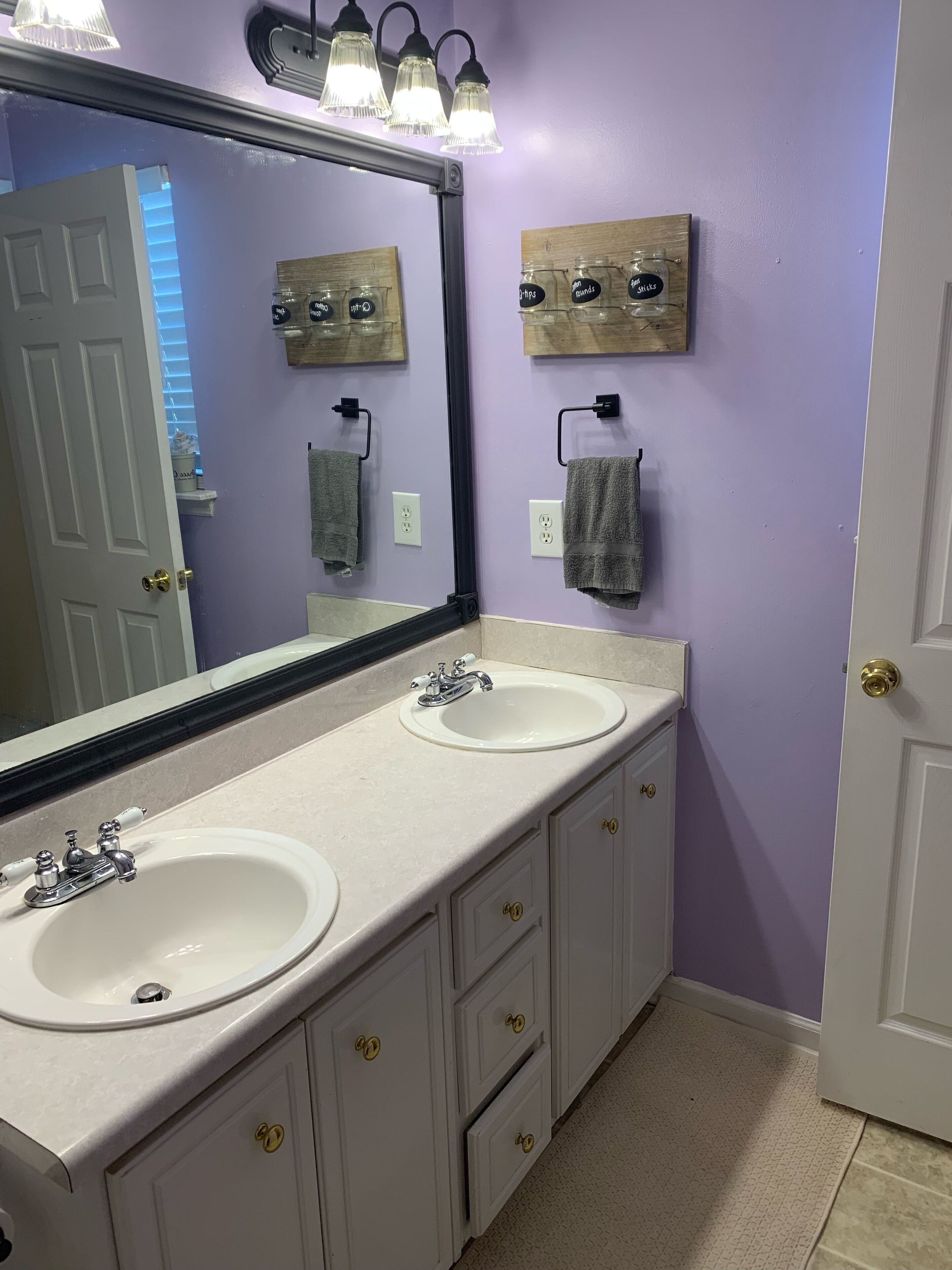 A bathroom with two sinks, a large mirror, and wooden wall decorations.