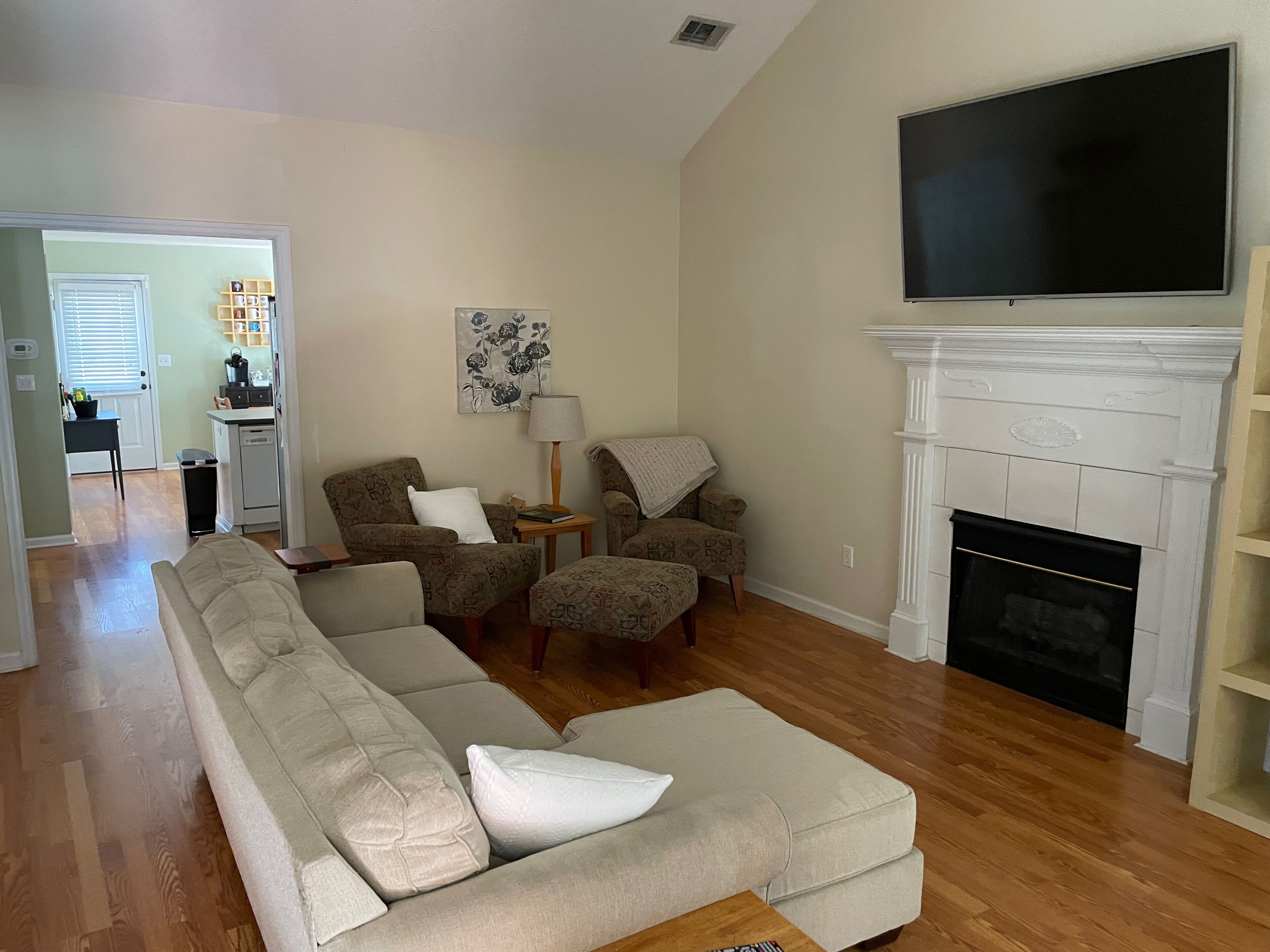 A living room with a sectional sofa, two armchairs, a fireplace, and a television.