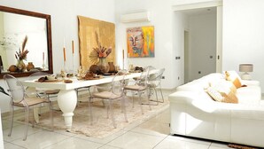 A modern dining area with a white table, clear chairs, and a white sofa. - Charming Villa in the Nature of Santa Gertrudis (Islas Baleares)