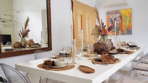 A dining area with a white table set for a meal, clear plastic chairs, and decorative items like vases and candles. - Charming Villa in the Nature of Santa Gertrudis (Islas Baleares)