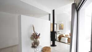 A modern living room with a white sofa, a black fireplace, and a glass door leading to another room. - Charming Villa in the Nature of Santa Gertrudis (Islas Baleares)