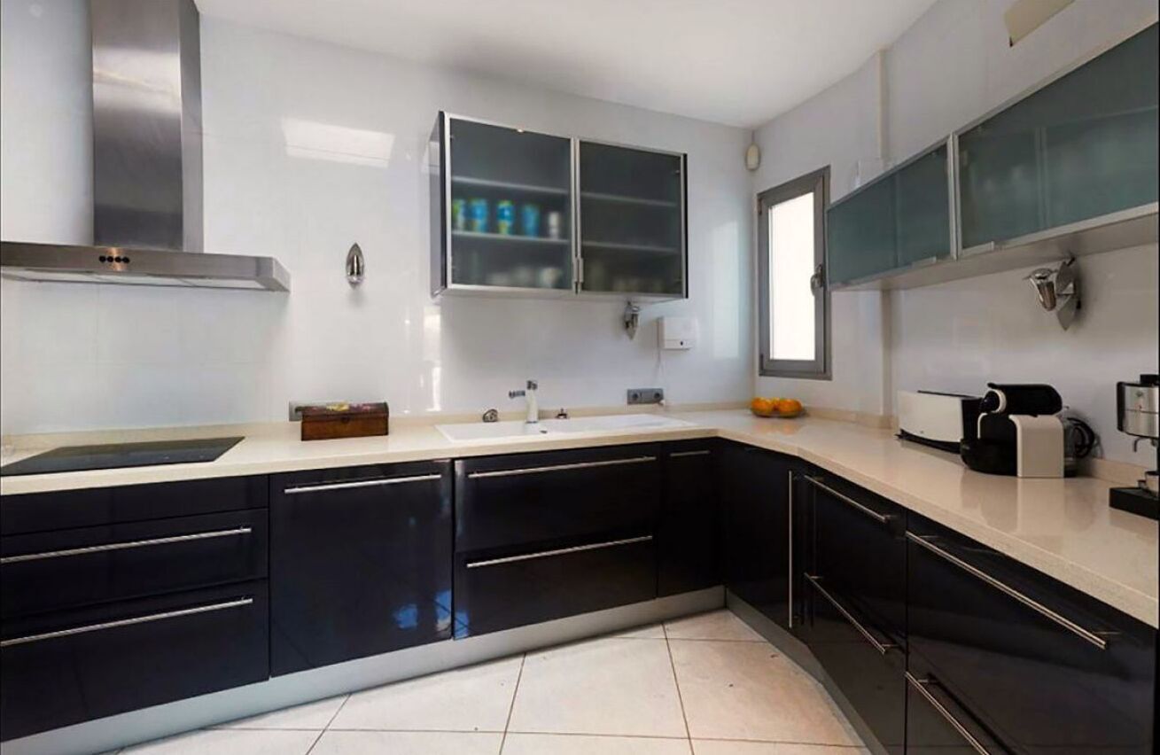 A modern kitchen with black cabinets, a white countertop, and a built-in oven.