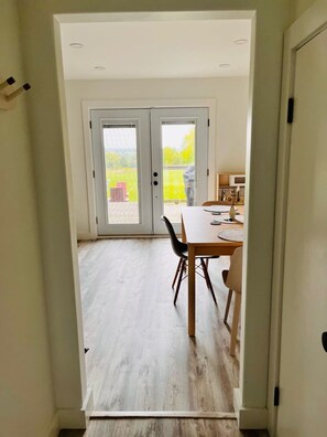 A view through a doorway into a dining area with a table and chairs, a sliding glass door leading outside, and a ceiling with recessed lighting. - The Blue House in the heart of Picton (Prince Edward)