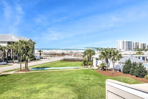 A residential area with a pool, palm trees, and a view of the beach and ocean.