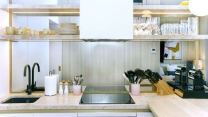 A modern kitchen with a double sink, stainless steel appliances, and a variety of utensils and cookware.