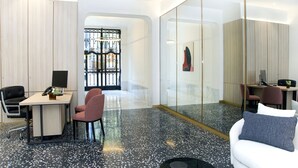 A modern office space with a desk, chairs, a sofa, and a glass partition.