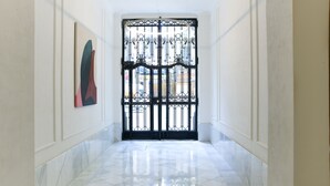 A hallway with a black wrought iron gate, white walls, and a tiled floor.