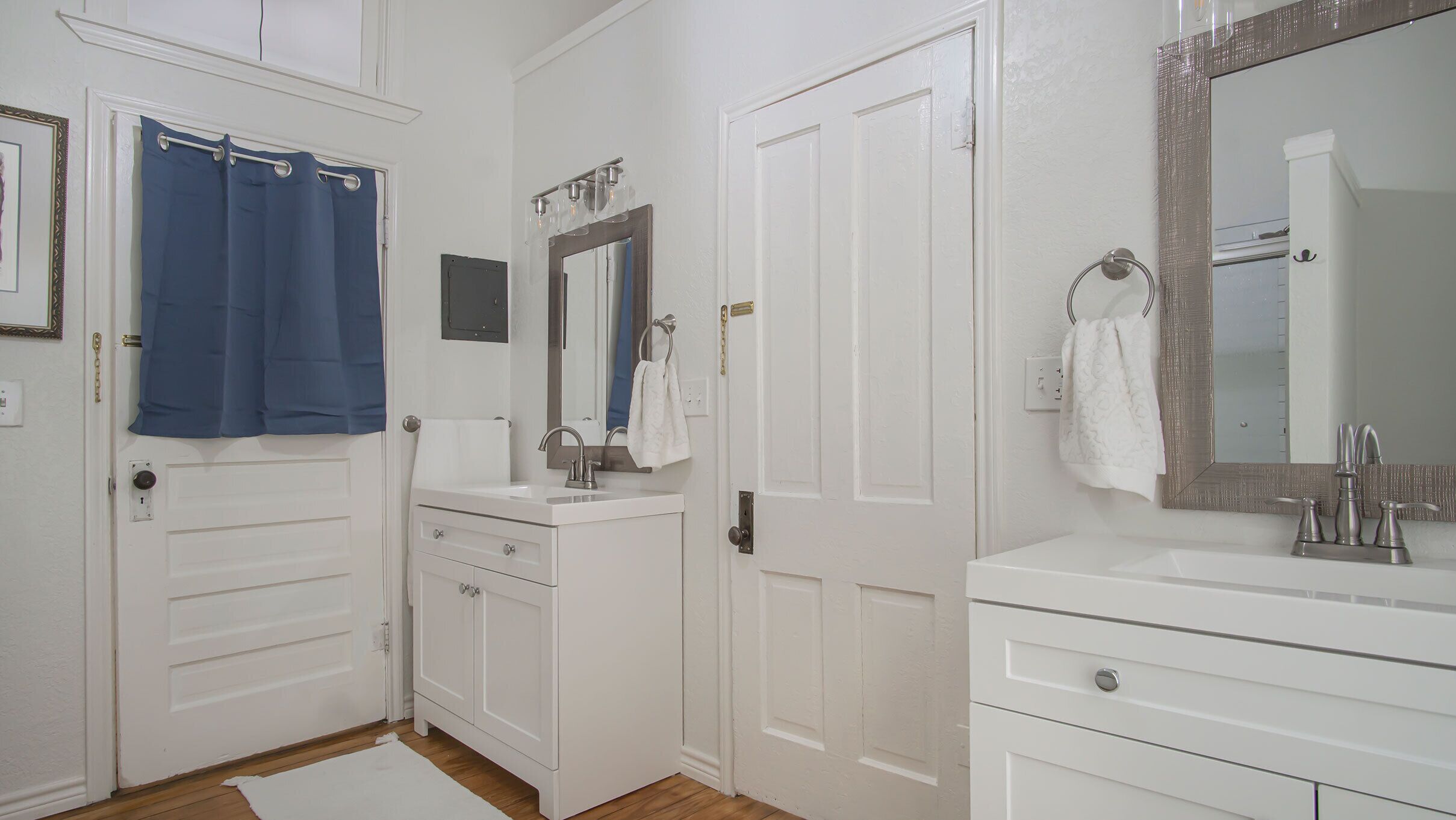 A bathroom with white cabinetry, a sink, a mirror, and a shower curtain.