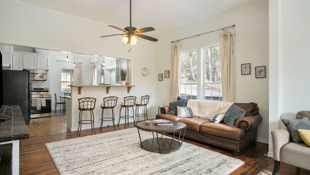 A modern living room with a brown leather sofa, a coffee table, and a dining area with bar stools. - Charming home, downtown Mineral Wells (Mineral Wells)