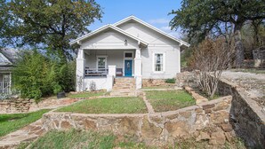 A white house with a blue door, stone steps, and a stone wall surrounding the property. - Charming home, downtown Mineral Wells (Mineral Wells)